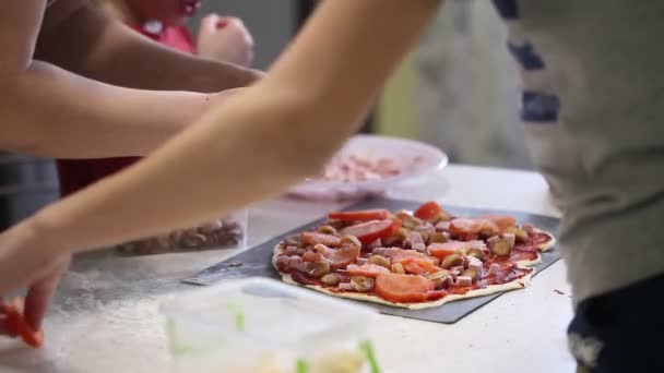 孩子们的手准备比萨饼 把馅料撒在面团上 — 图库视频影像