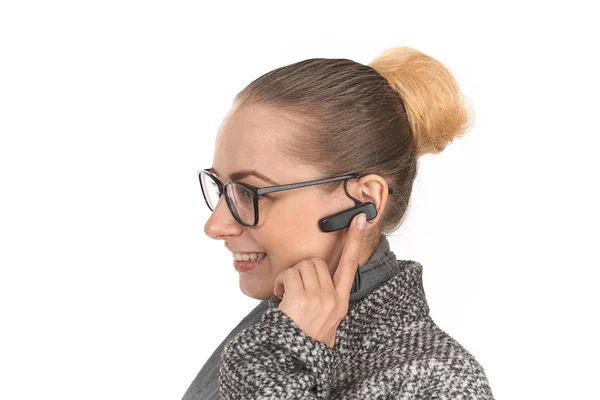 Retrato de cerca de una chica sobre un fondo blanco con un auricular manos libres . — Foto de Stock