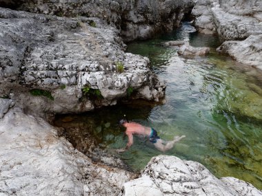 a man swims in a mountain river. Italy