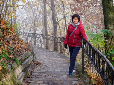 Sonbahar sisli parkında güzel neşeli bir kadın.