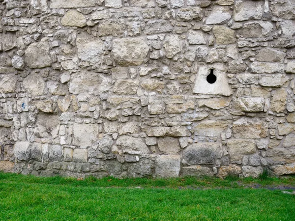 Yeşil çimenlikte taş beyaz duvar — Stok fotoğraf