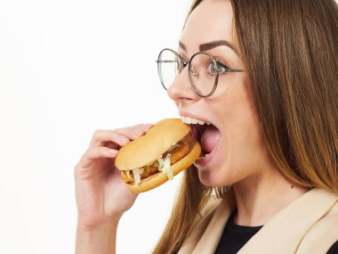 Beyaz arka planda hamburger yiyen bir kız.