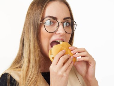 Beyaz arka planda hamburger yiyen bir kız.