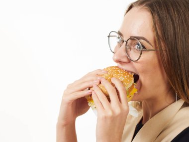 Beyaz arka planda hamburger yiyen bir kız.