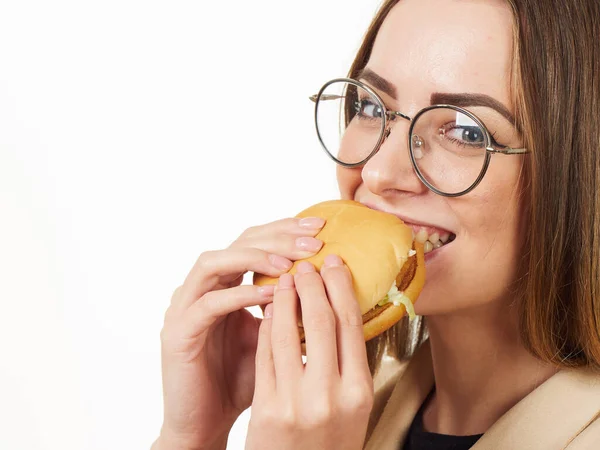 Ragazza mangiare un hamburger su uno sfondo bianco — Foto Stock