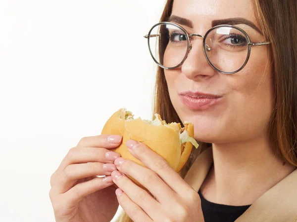 Menina comer um hambúrguer em um fundo branco — Fotografia de Stock