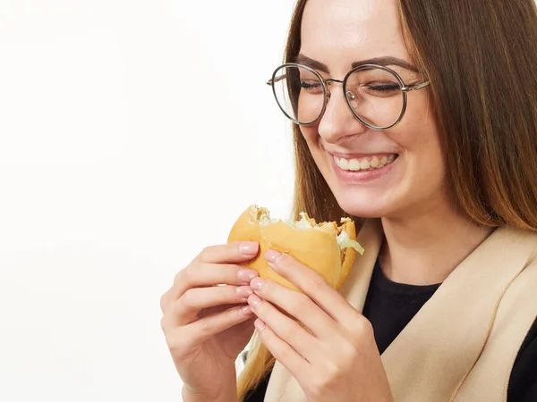 Girl eating a burger on a white background — Stock Photo, Image