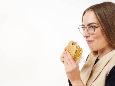 Beyaz arka planda hamburger yiyen bir kız.