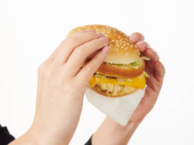 Beyaz arka planda hamburger yiyen bir kız.