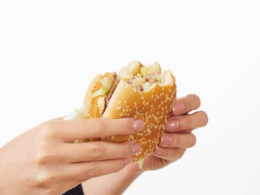 Beyaz arka planda hamburger yiyen bir kız.