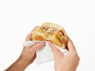 Beyaz arka planda hamburger yiyen bir kız.