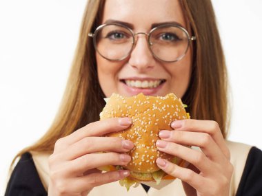 Beyaz arka planda hamburger yiyen bir kız.