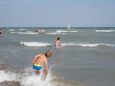 Çocuklar İtalya 'nın Bibione plajında denizde yüzerler.