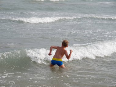 Çocuklar İtalya 'nın Bibione plajında denizde yüzerler.