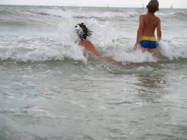 Anne ve oğlu denizde yüzüyorlar. Bibione, İtalya