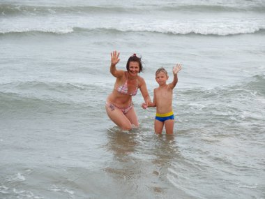 Anne ve oğlu denizde yüzüyorlar. Bibione, İtalya