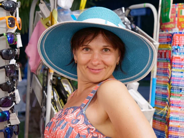 Mulher mede chapéu e óculos na loja — Fotografia de Stock