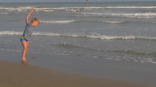 Menino atlético na praia em salto no fundo do mar e do céu — Vídeo de Stock