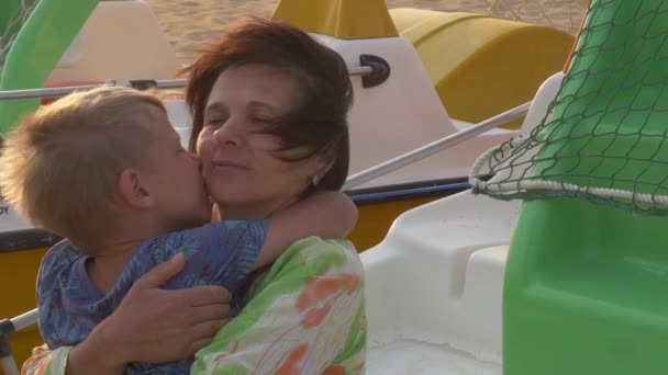 Mama przytula syna na brzegu morza na wietrze — Wideo stockowe