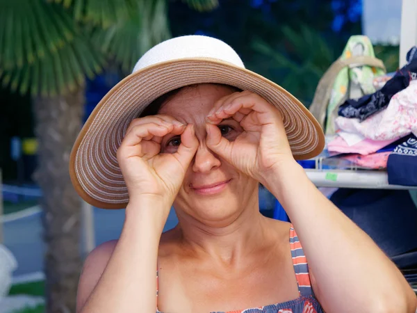 Žena měří klobouk a brýle na skladě — Stock fotografie