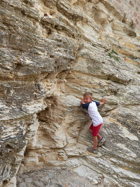 Chłopiec wspina się na skałę na ulicy starego miasta Arkua Petrarka, Włochy — Zdjęcie stockowe