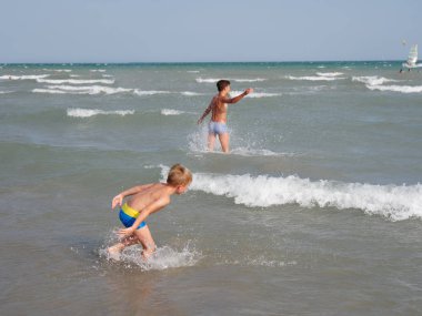 Çocuklar İtalya 'nın Bibione plajında denizde yüzerler.