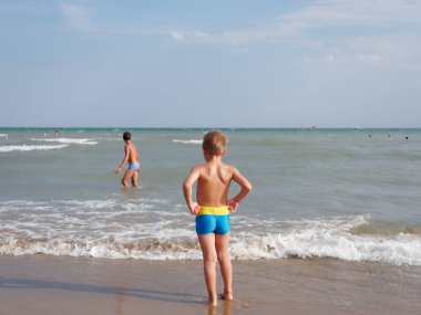 Çocuklar İtalya 'nın Bibione plajında denizde yüzerler.