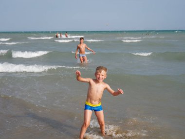 Çocuklar İtalya 'nın Bibione plajında denizde yüzerler.
