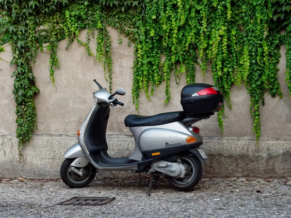 MONTANYANA, ITALIA - 26 DE AGOSTO DE 2019: ciclomotor en el fondo de una pared de piedra con enredaderas . — Foto de Stock