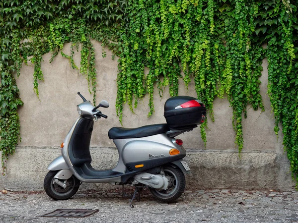 MONTANYANA, ITALIA - 26 DE AGOSTO DE 2019: ciclomotor en el fondo de una pared de piedra con enredaderas . — Foto de Stock