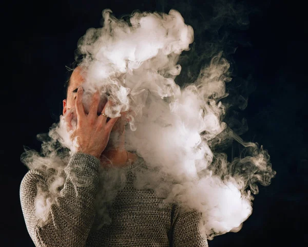Hombre fumador en humo de cigarrillo electrónico sobre fondo negro —  Fotos de Stock
