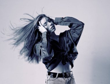 Gri bir arka planda dans eden uzun saçlı genç bir kız.