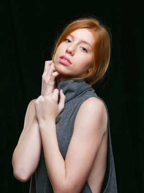 Siyah arka planda uzun kızıl saçlı genç bir kız.