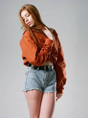 Gri arka planda uzun kızıl saçlı genç bir kız.