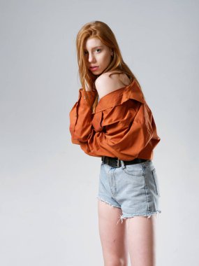 Gri arka planda uzun kızıl saçlı genç bir kız.