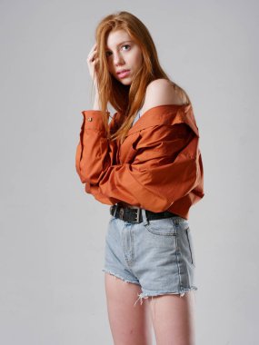 Gri arka planda uzun kızıl saçlı genç bir kız.