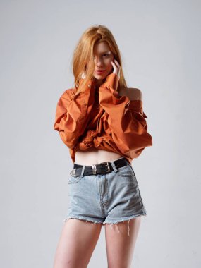 Gri arka planda uzun kızıl saçlı genç bir kız.