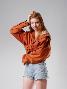 Gri arka planda uzun kızıl saçlı genç bir kız.