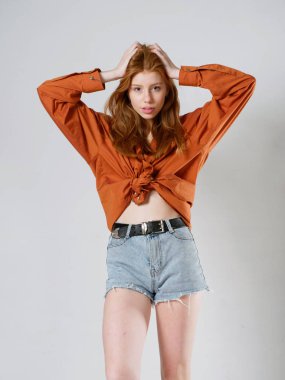 Gri arka planda uzun kızıl saçlı genç bir kız.