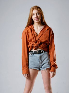 Gri arka planda uzun kızıl saçlı genç bir kız.