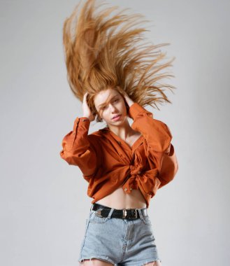 Gri arka planda uzun kızıl saçlı genç bir kız.