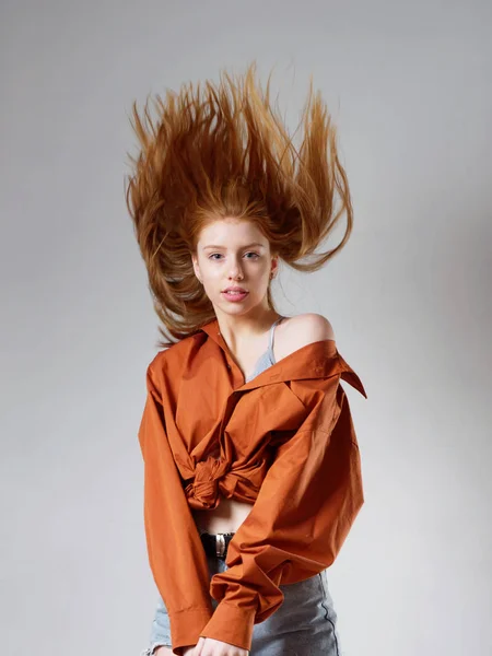 Chica joven con el pelo largo y rojo sobre un fondo gris — Foto de Stock