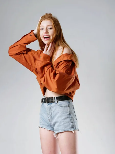 Chica joven con el pelo largo y rojo sobre un fondo gris —  Fotos de Stock