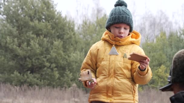 6岁的男孩在大自然中吃着生火的面包 — 图库视频影像