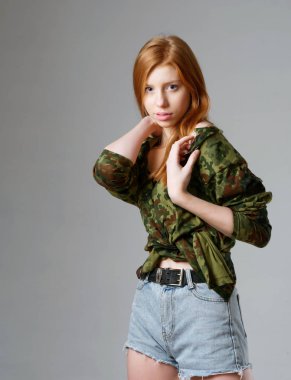 Gri arka planda uzun kızıl saçlı genç bir kız.