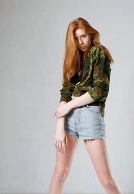 Gri arka planda uzun kızıl saçlı genç bir kız.