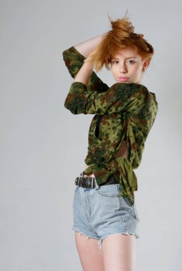 Gri arka planda uzun kızıl saçlı genç bir kız.