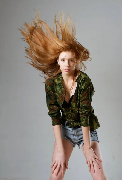 Ung flicka med långt rött hår på en grå bakgrund — Stockfoto
