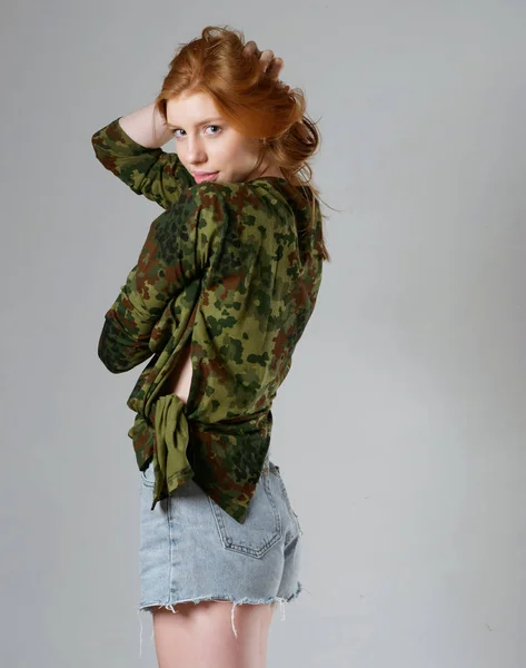 Chica joven con el pelo largo y rojo sobre un fondo gris —  Fotos de Stock