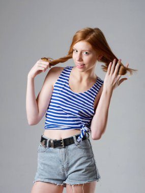 Gri arka planda uzun kızıl saçlı genç bir kız.